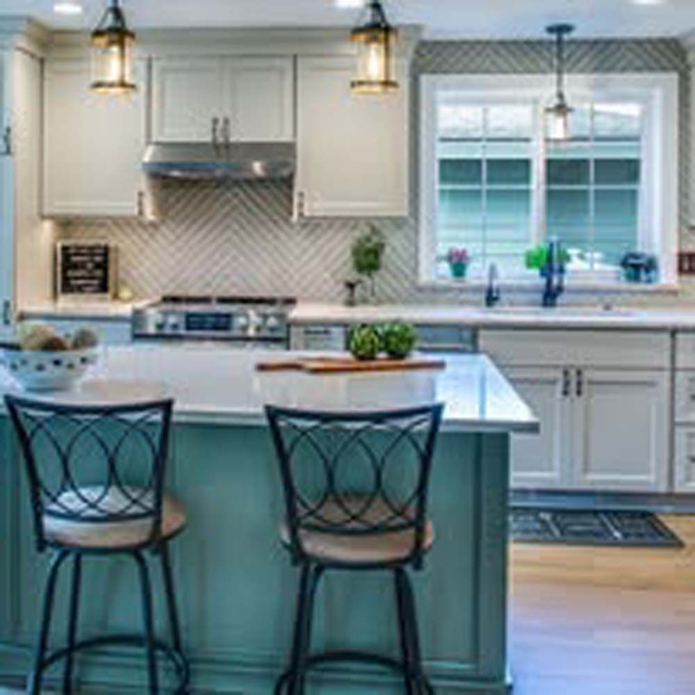 Kitchen with island, bar stools, and white cabinetry. Stainless steel appliances and a window are visible.