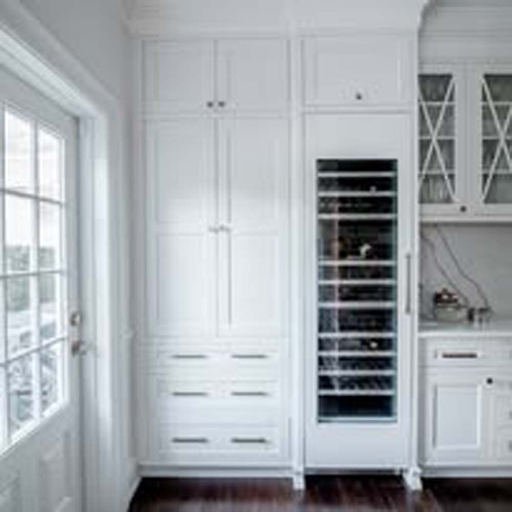 White kitchen cabinets with wine fridge next to a windowed door.