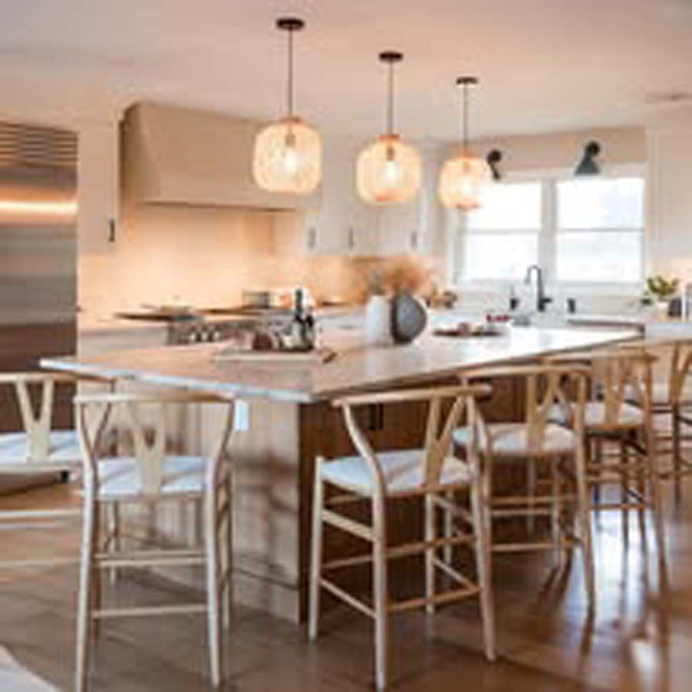 Kitchen island with light wood bar stools and hanging globe lights.