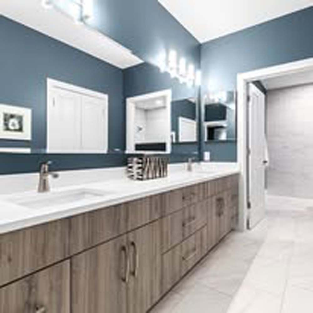 Bathroom with blue walls, double sinks, wood cabinets, and large mirror.