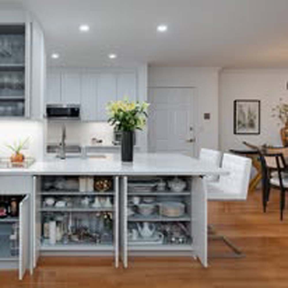 Modern kitchen with white cabinets, island storage, and wood flooring.