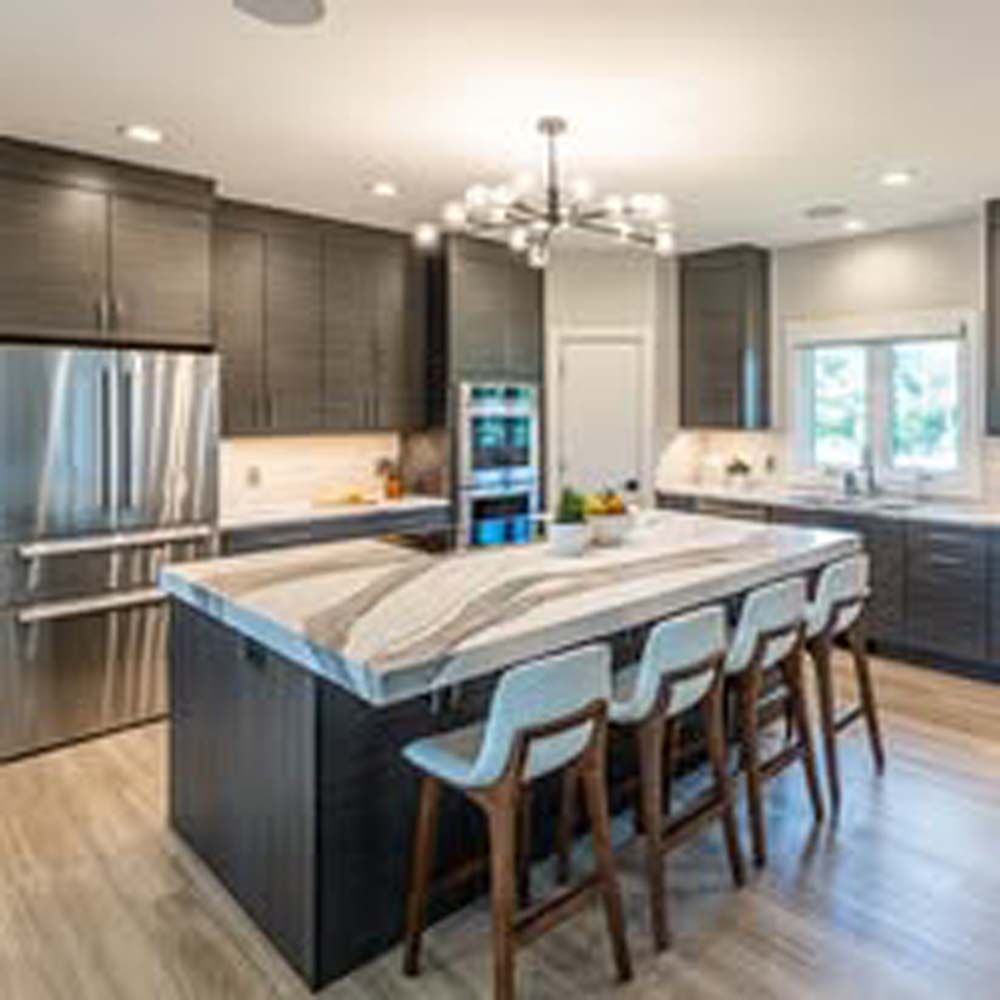 Modern kitchen with dark cabinetry, large island, and chandelier.