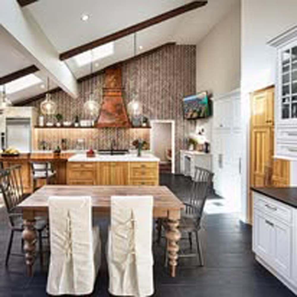 Rustic kitchen with wood cabinets, copper range hood, and wooden dining table.