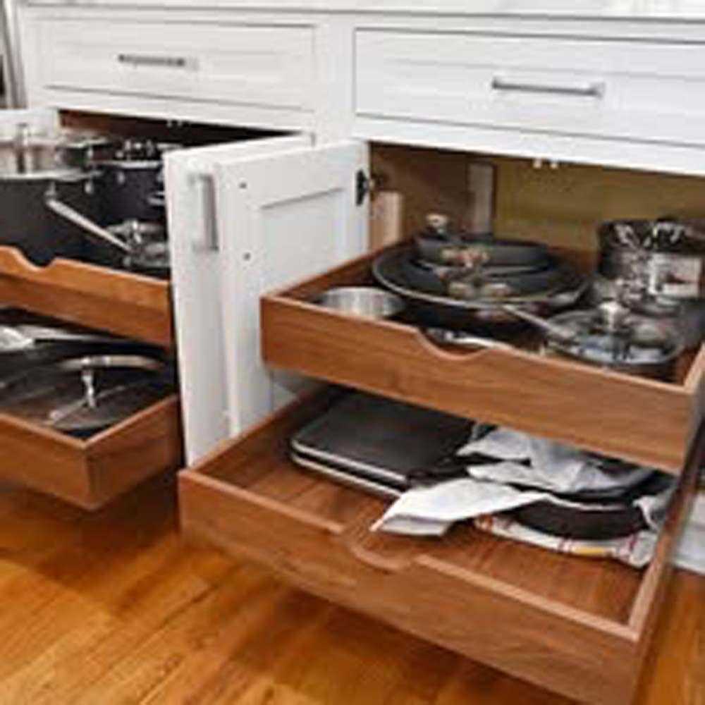 Kitchen cabinets with pull-out drawers holding cookware and a pot; wood floors.