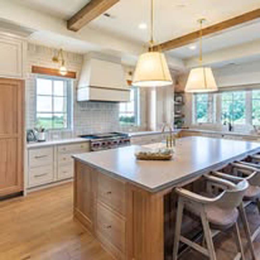 Spacious kitchen with wood island, pendant lights, and large windows.