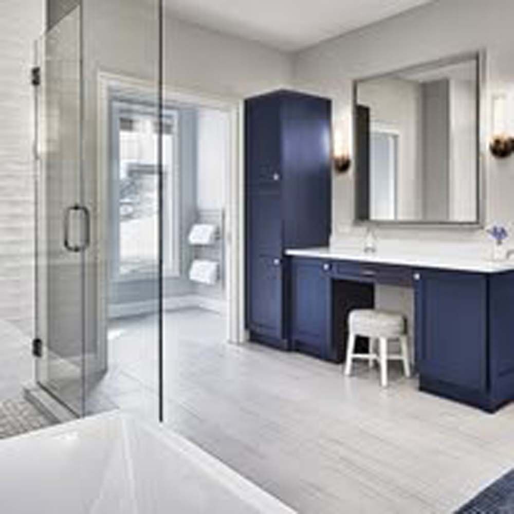 Modern navy blue bathroom with a walk-in shower, vanity, and storage cabinet.