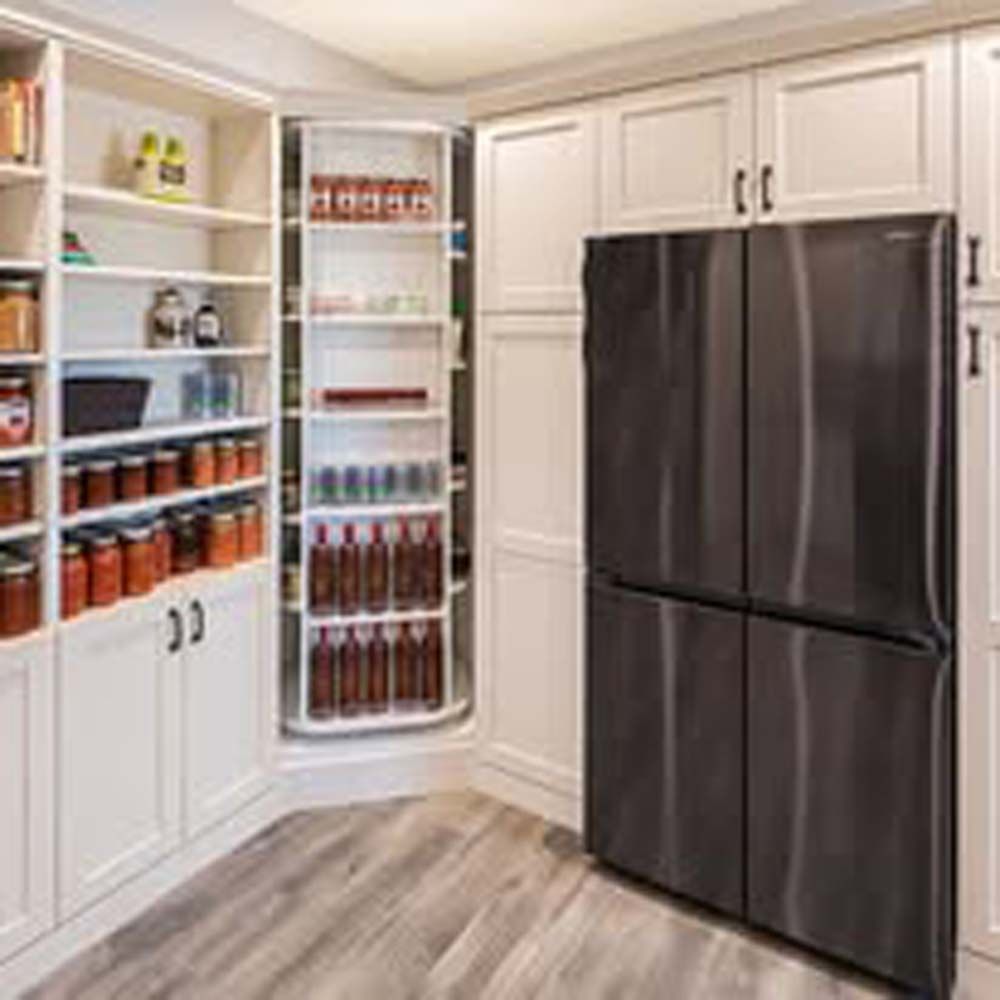 Pantry with a rotating shelving unit and a dark stainless steel refrigerator.