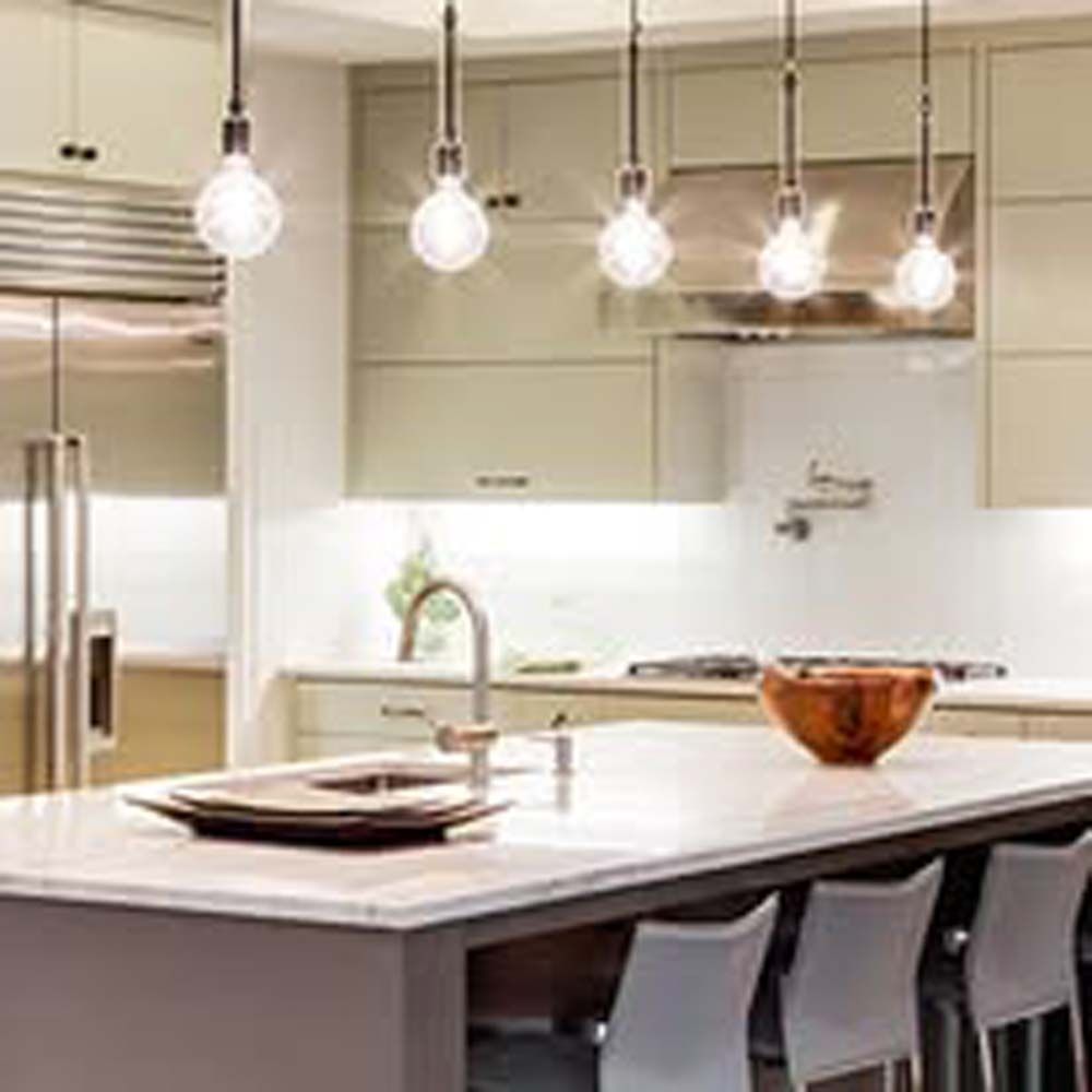 Modern kitchen with island, pendant lights, stainless steel appliances, and beige cabinets.