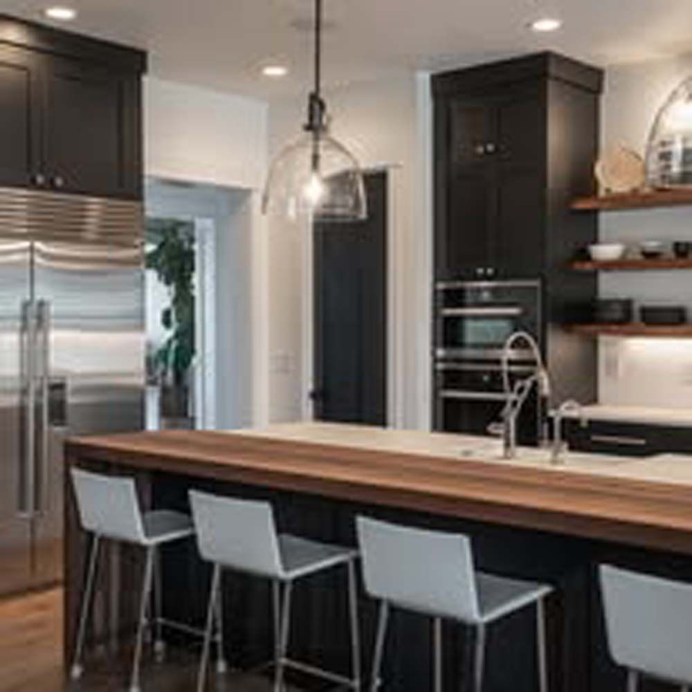 Kitchen with black cabinets, wood countertop, and bar stools.