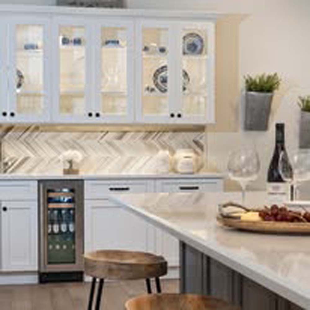 Kitchen with white cabinets, wine cooler, and marble countertop.