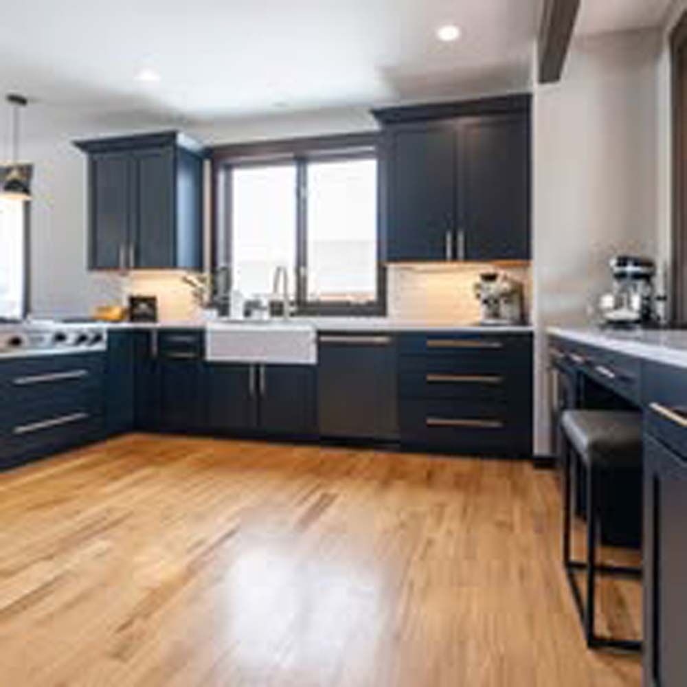 Kitchen with dark blue cabinets, light wood floor, and large window.