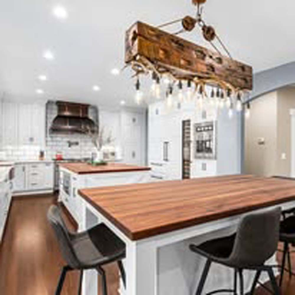 Kitchen with wood countertops, white cabinets, a large wood chandelier, and chairs.