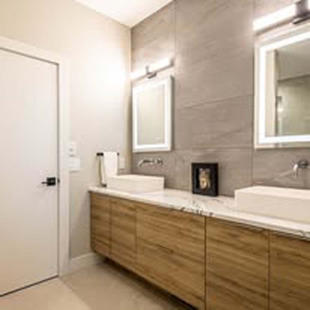 Modern bathroom with wooden vanity, two sinks, and large mirror.