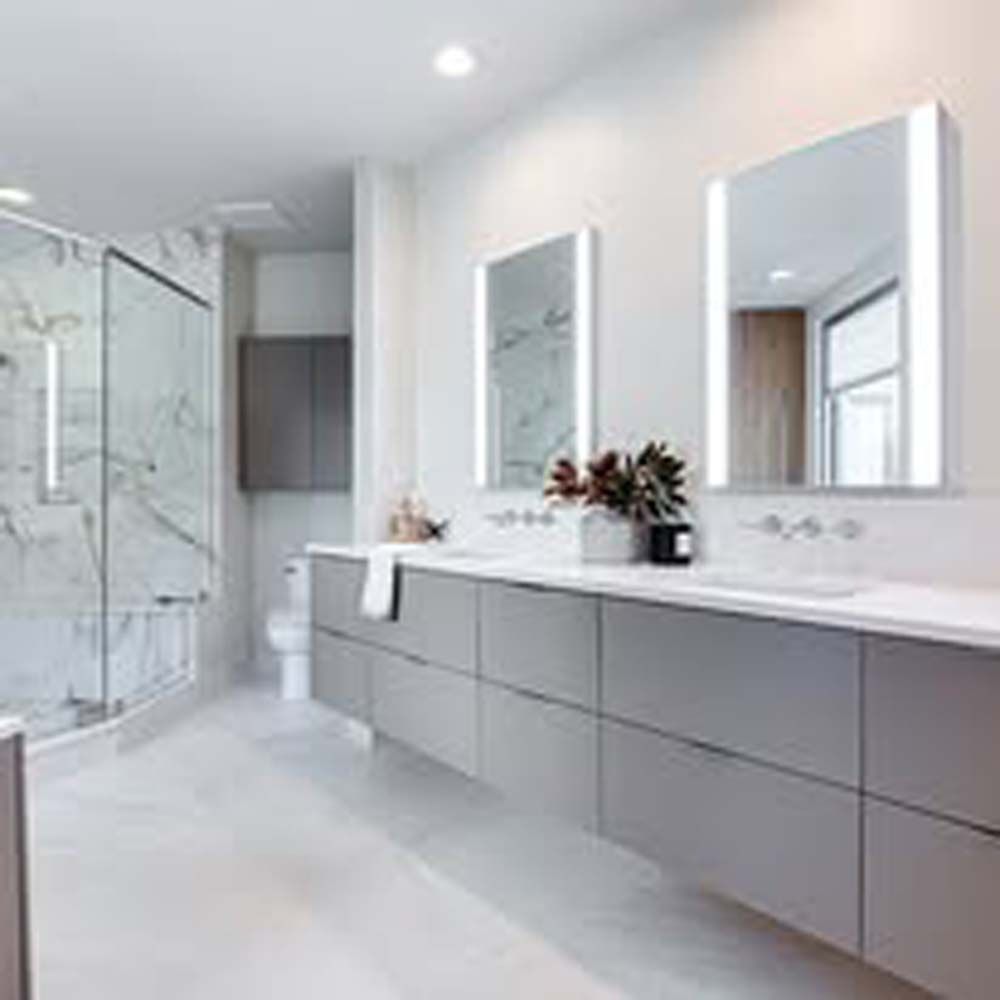 Modern bathroom with double sink vanity, backlit mirrors, and glass shower.