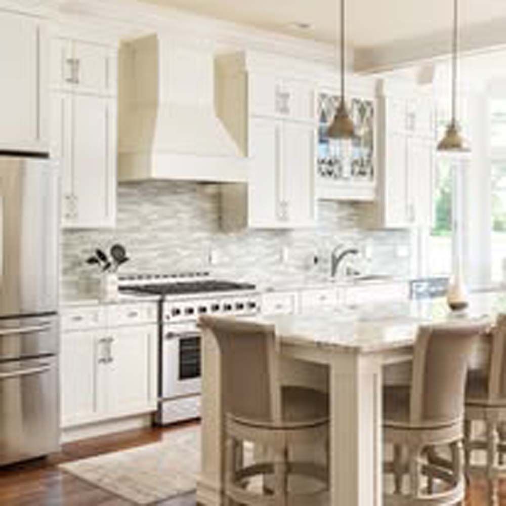 White kitchen with stainless steel appliances, marble countertop, and bar stools.