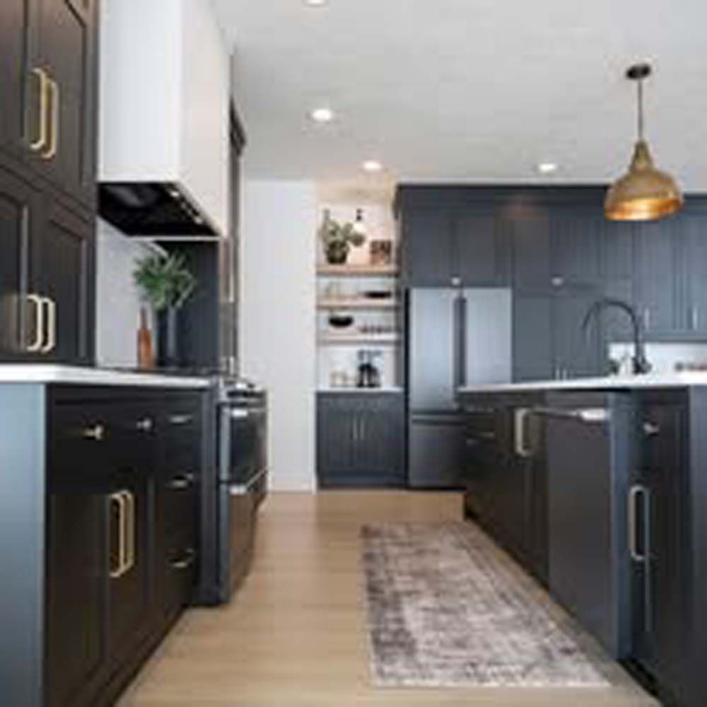 Modern kitchen with dark cabinets, gold hardware, and wooden floors.