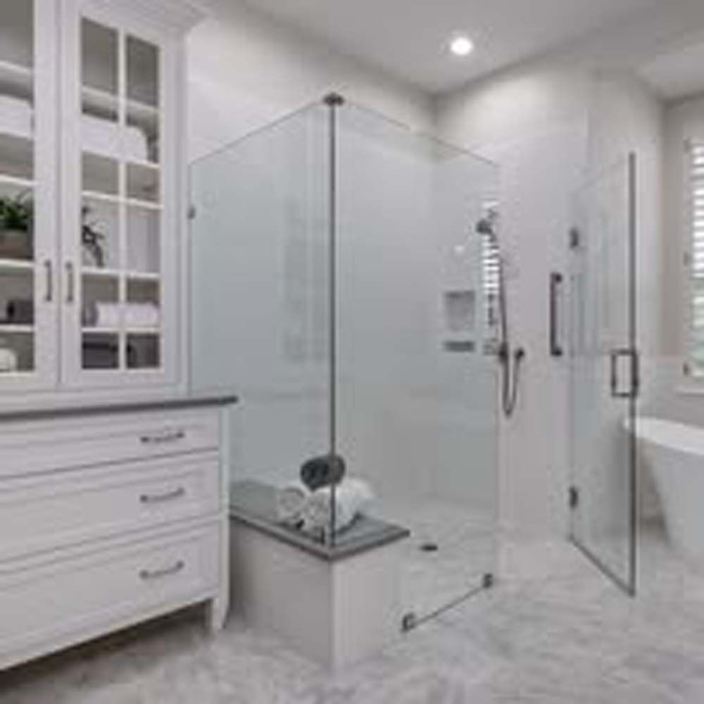 A modern, white bathroom with glass shower, built-in shelving, drawers, and marble floors.
