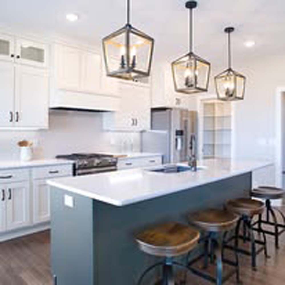 Modern kitchen with white cabinets, blue island, pendant lights, and wooden stools.