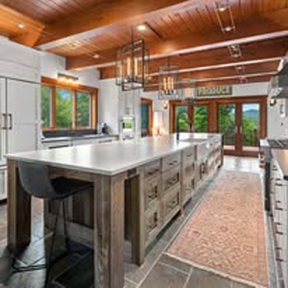 Spacious kitchen with large island, wood beams, and a view of mountains.