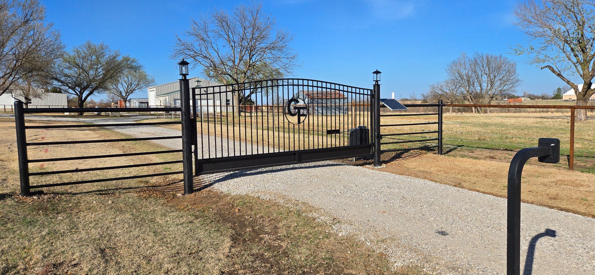 Black Swinging drive gate on gravel road