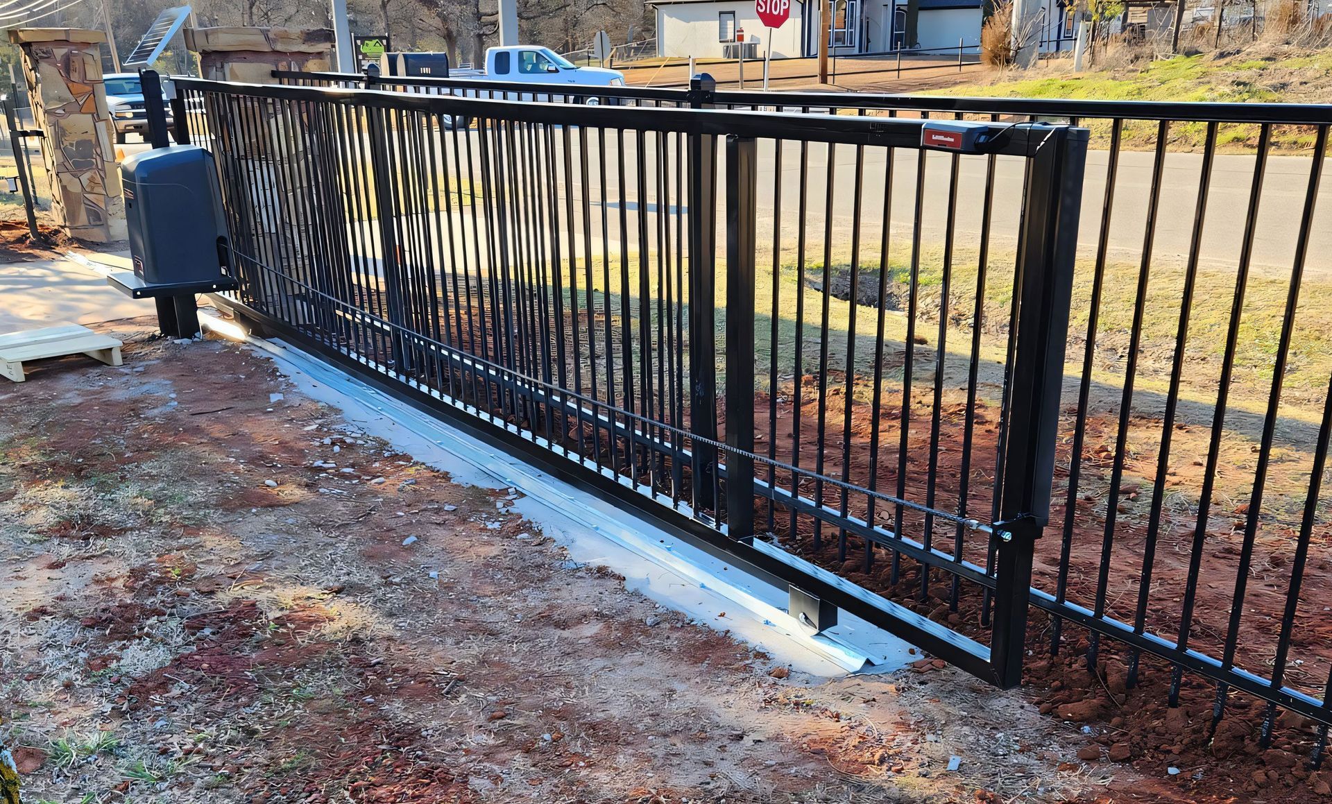 A black sliding gate is sitting in the dirt next to a road