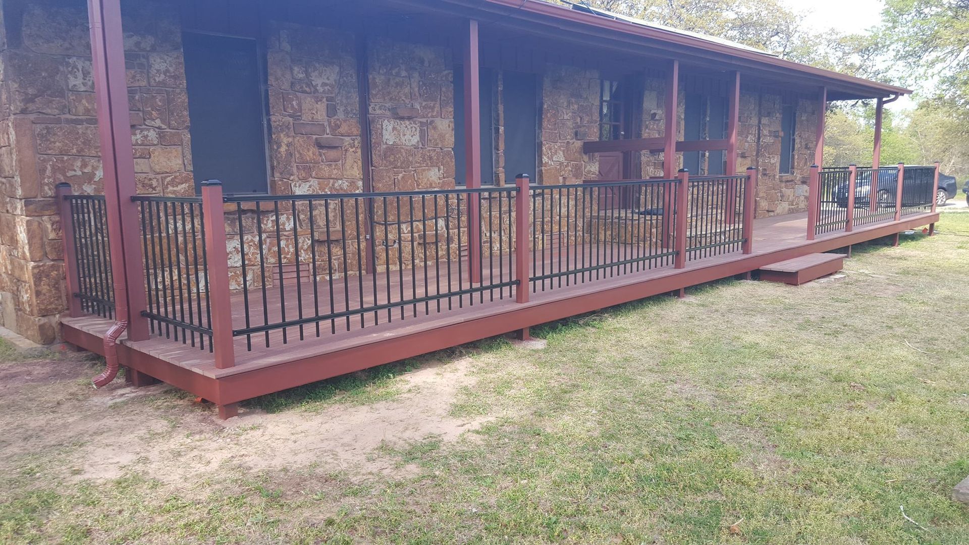A stone house with a large porch and a metal railing