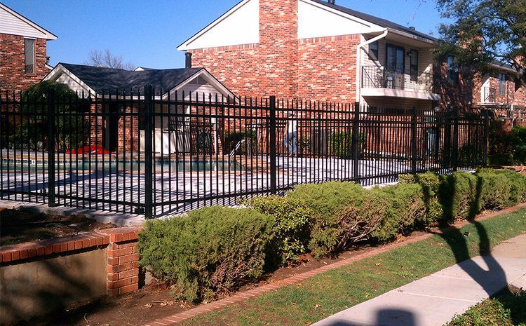 A fence surrounds a swimming pool in front of a brick building