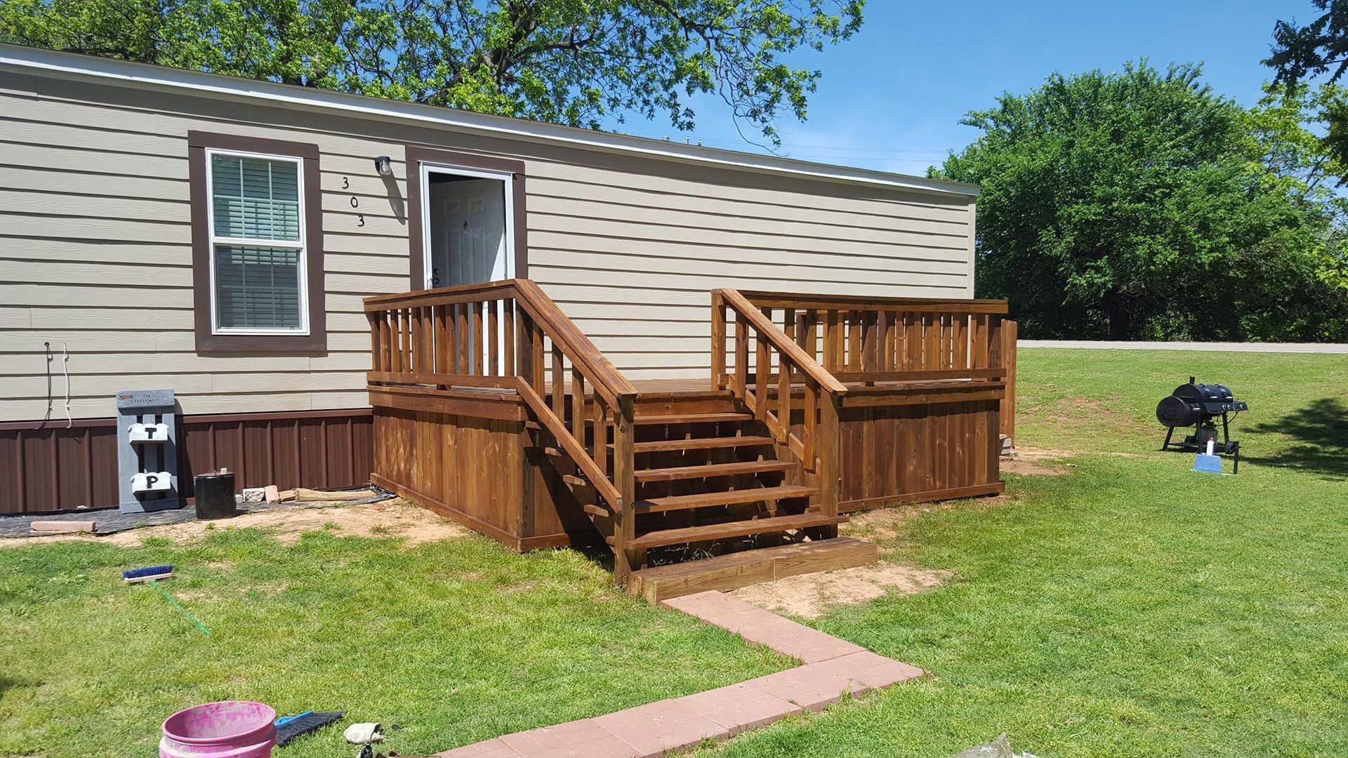 A mobile home with a wooden deck and stairs in front of it