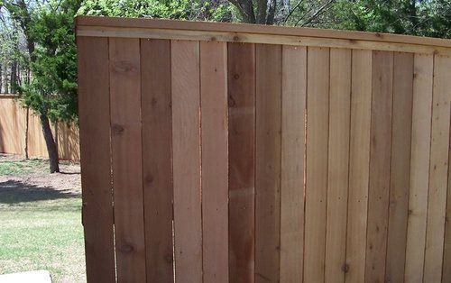 A close up of a wooden fence with trees in the background