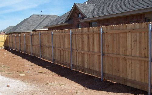 A wooden fence in front of a brick house