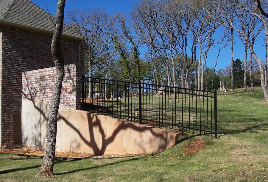 A brick house with a black fence in front of it.