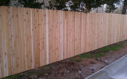 A wooden fence is sitting next to a sidewalk.