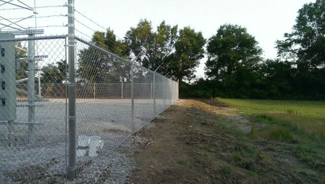 A chain link fence is surrounding a building in a field.