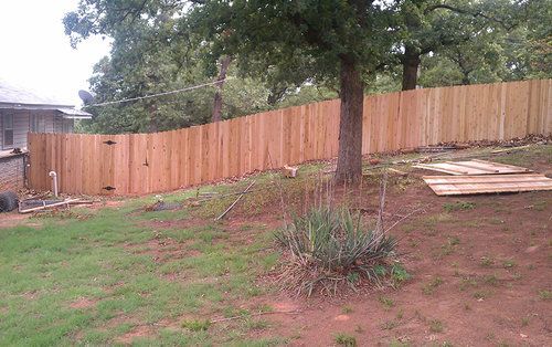 A wooden fence is being built in the backyard of a house.
