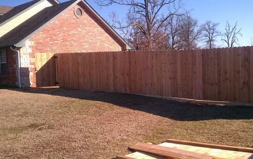 A wooden fence is in the backyard of a house.
