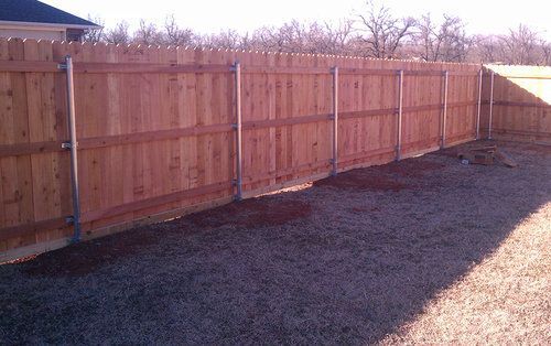 A wooden fence is in the backyard of a house.