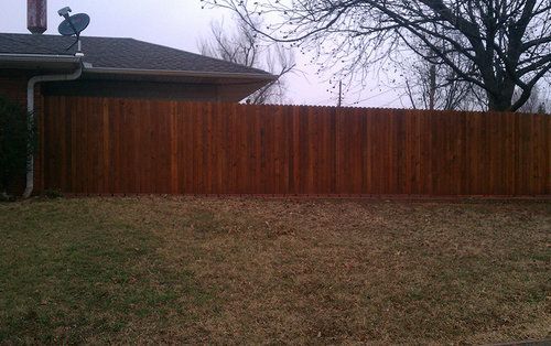 A wooden fence is in the backyard of a house.