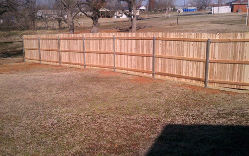 A wooden fence is in the middle of a grassy field.