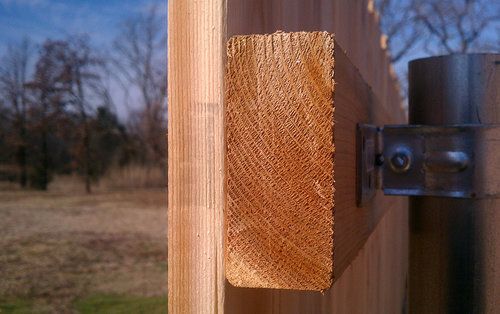A piece of wood is sitting on top of a wooden fence post.