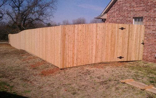 A wooden fence with a gate in front of a brick house.