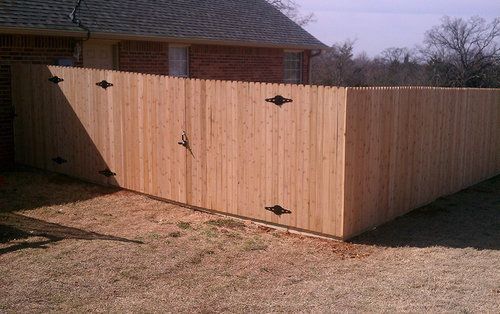 A wooden fence is sitting in front of a brick house.
