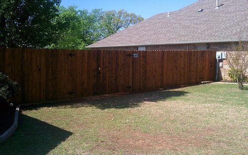 A wooden fence is in the backyard of a house.