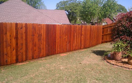 A wooden fence is in the backyard of a house.