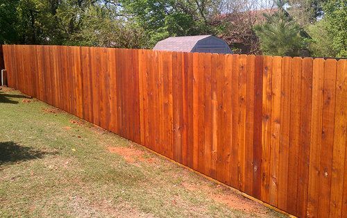 A wooden fence is sitting on top of a lush green field.