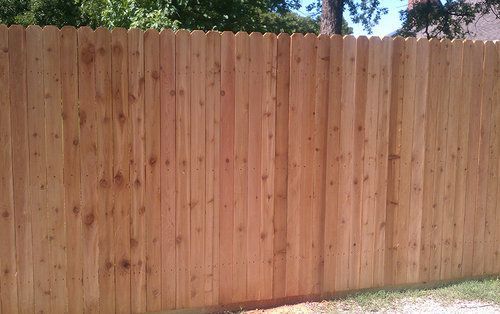 A close up of a wooden fence with trees in the background.