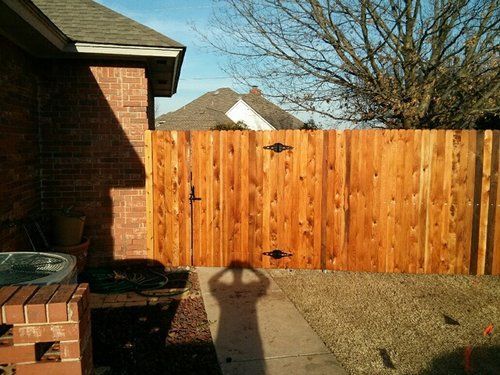 A wooden fence with a gate in the backyard of a house