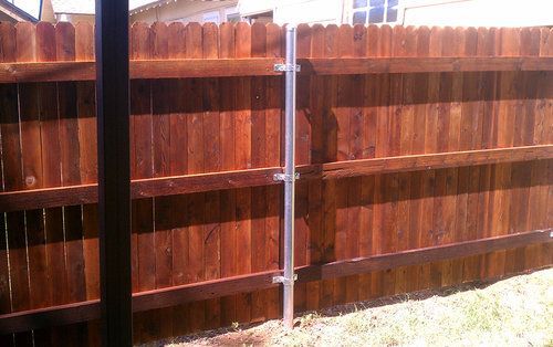 A wooden fence with a metal post in the backyard.