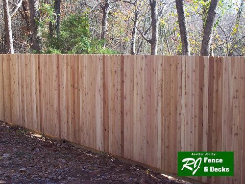A wooden fence with a green sign that says rj fence & decks