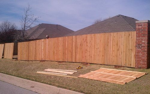 A wooden fence is being built in front of a house.