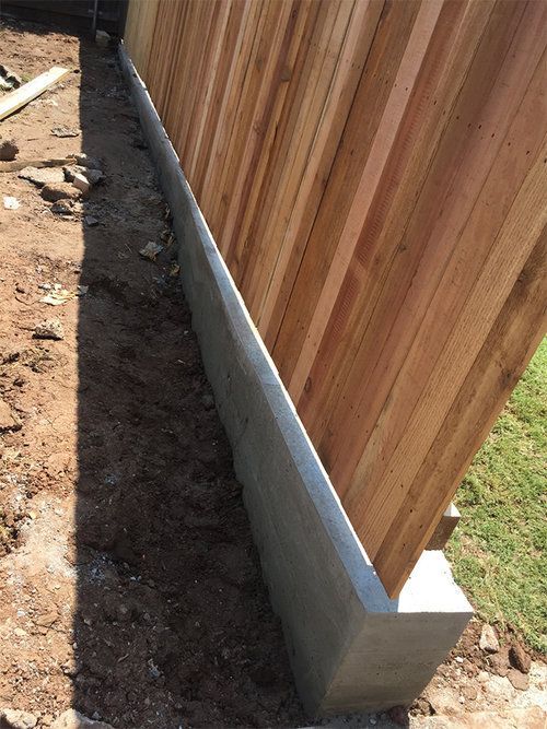 A wooden fence is being built next to a concrete foundation.